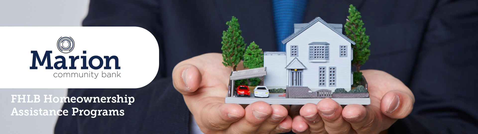 Image of a small house being held up by a loan agent. Overlaying text reads: FHLB Homeownership Assistance Programs