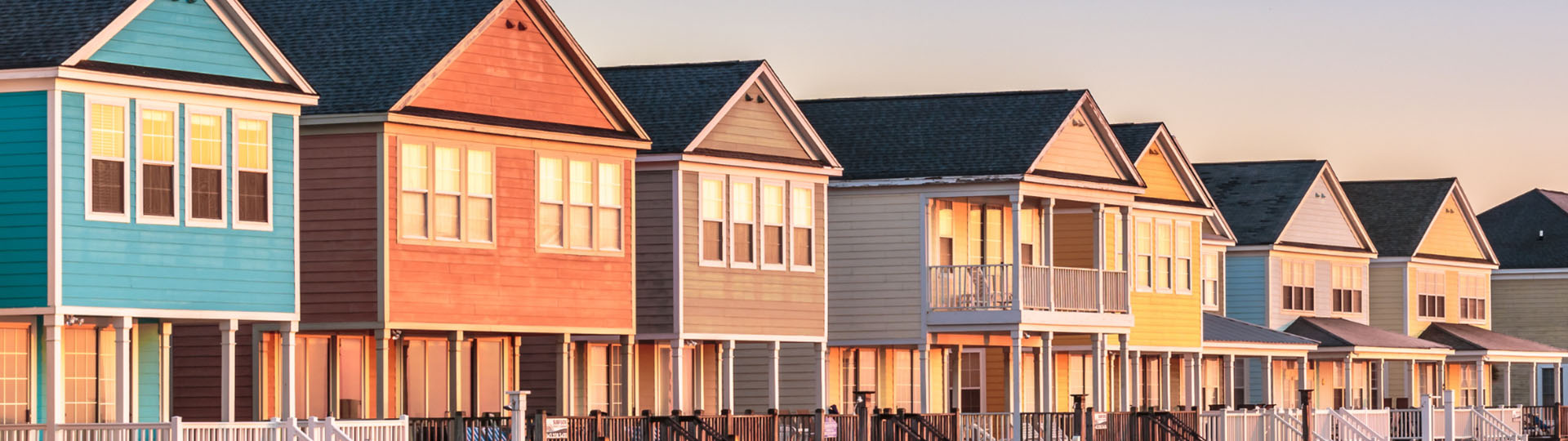 Row of colorful homes reflecting a sunset.