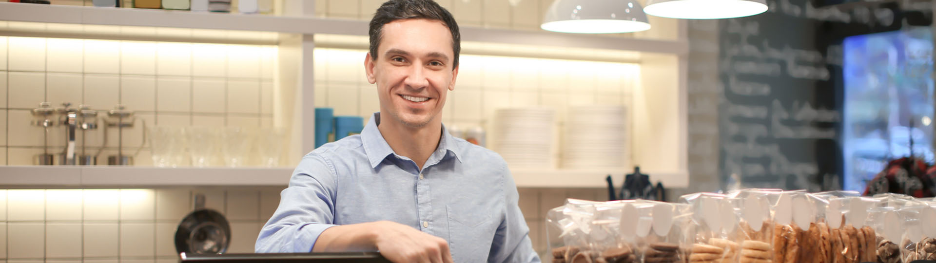 Man smiling behind a pastry counter.