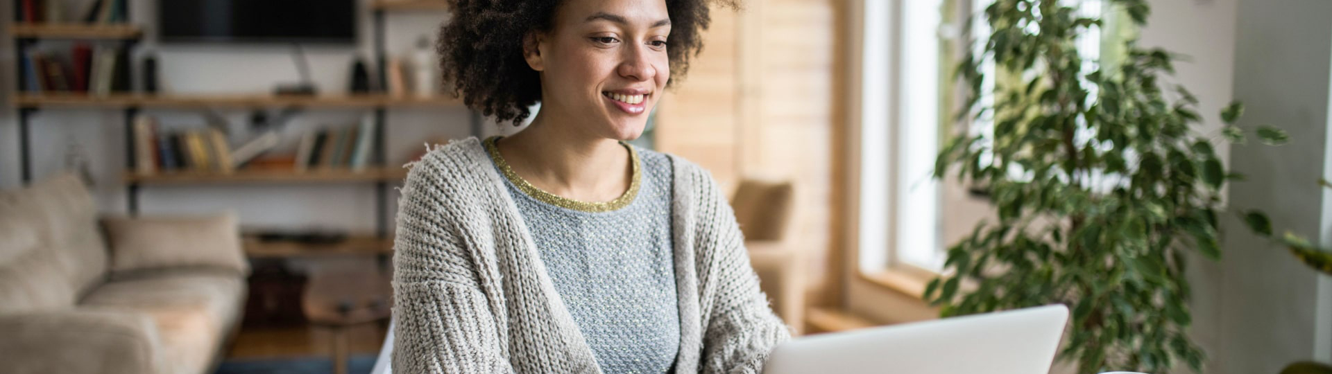 Smiling woman sitting at her laptop and drinking coffee.
