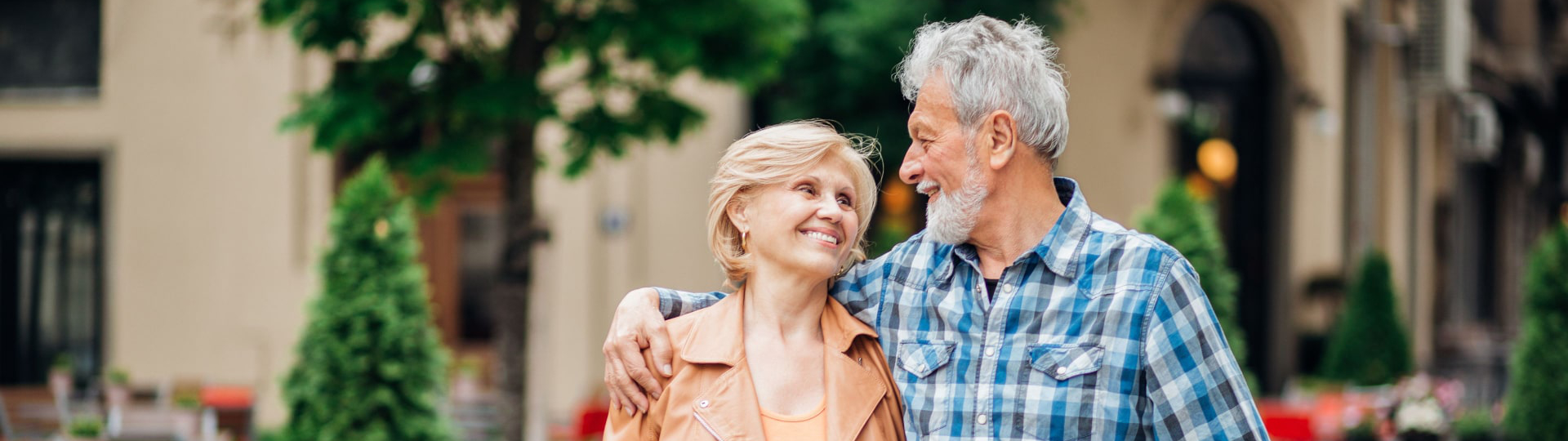 Happy older couple walking with their arms around each other's shoulders.